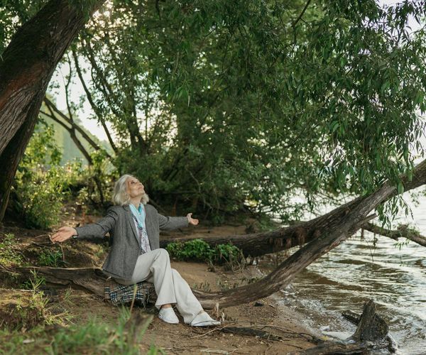 Person meditating peacefully outdoors near a calm lake.